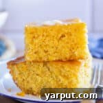 A beautifully baked piece of cornbread with a crispy edge and soft, golden interior, featuring a hint of corn kernels, ready to be enjoyed.
