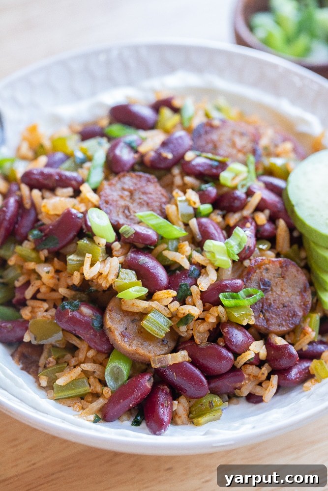 Easy Plant-Based Meals: Week 13 4 Skillet Vegetarian Sausage with Red Beans and Rice, garnished with fresh herbs and served with lime.
