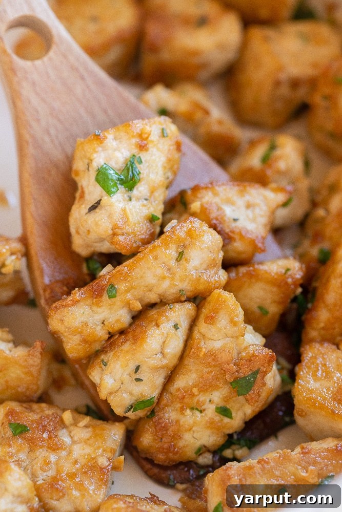 Close up of garlic butter tofu being cooked in a pan, achieving a golden brown color