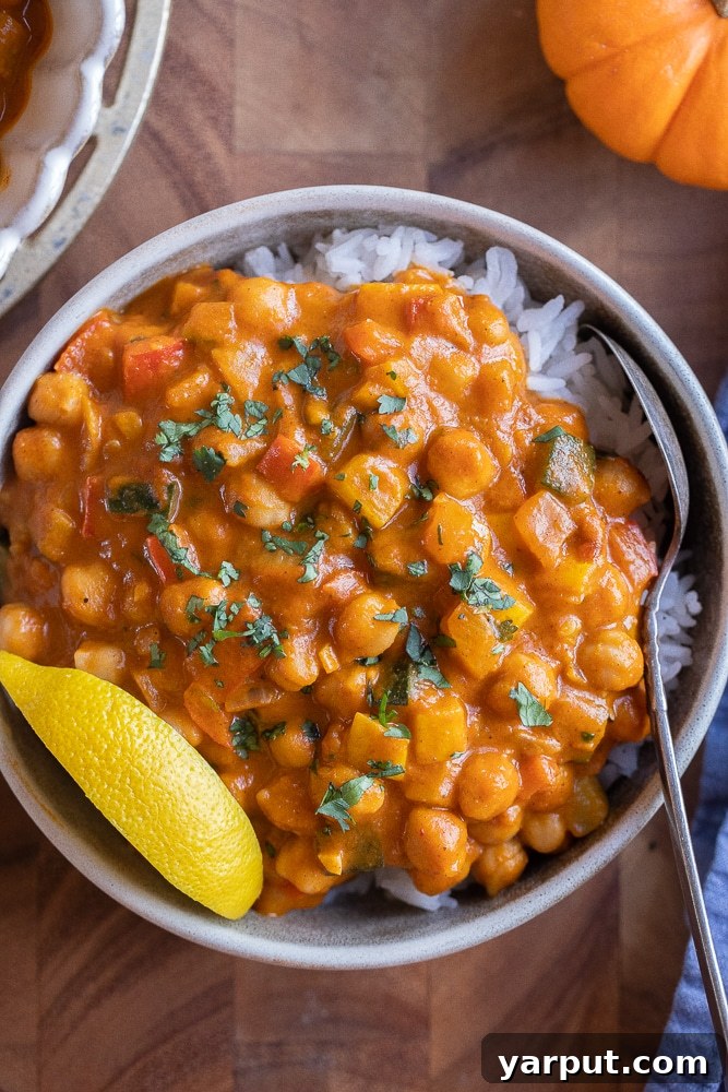 A World of Lentil Chickpea and Bean Delights 16 A rich pumpkin red curry with chickpeas and assorted vegetables, served in a bowl.