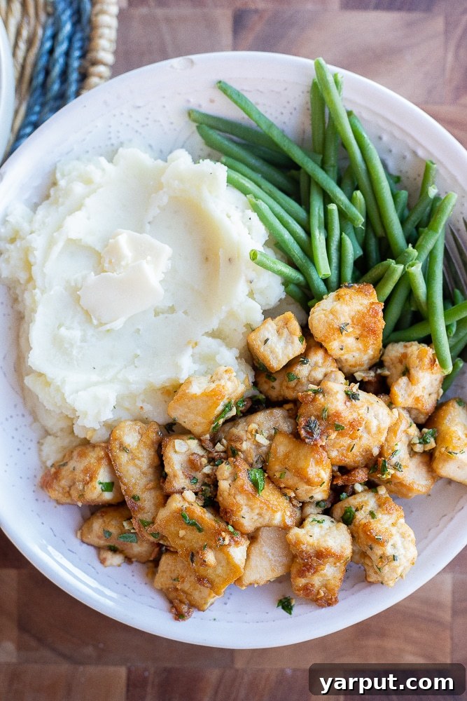 Golden-brown Garlic Butter Tofu Bites served in a bowl, garnished with fresh herbs.