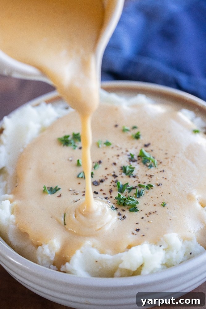 The Ultimate Vegetarian Gravy 7 gravy being poured onto a bowl of fluffy mashed potatoes