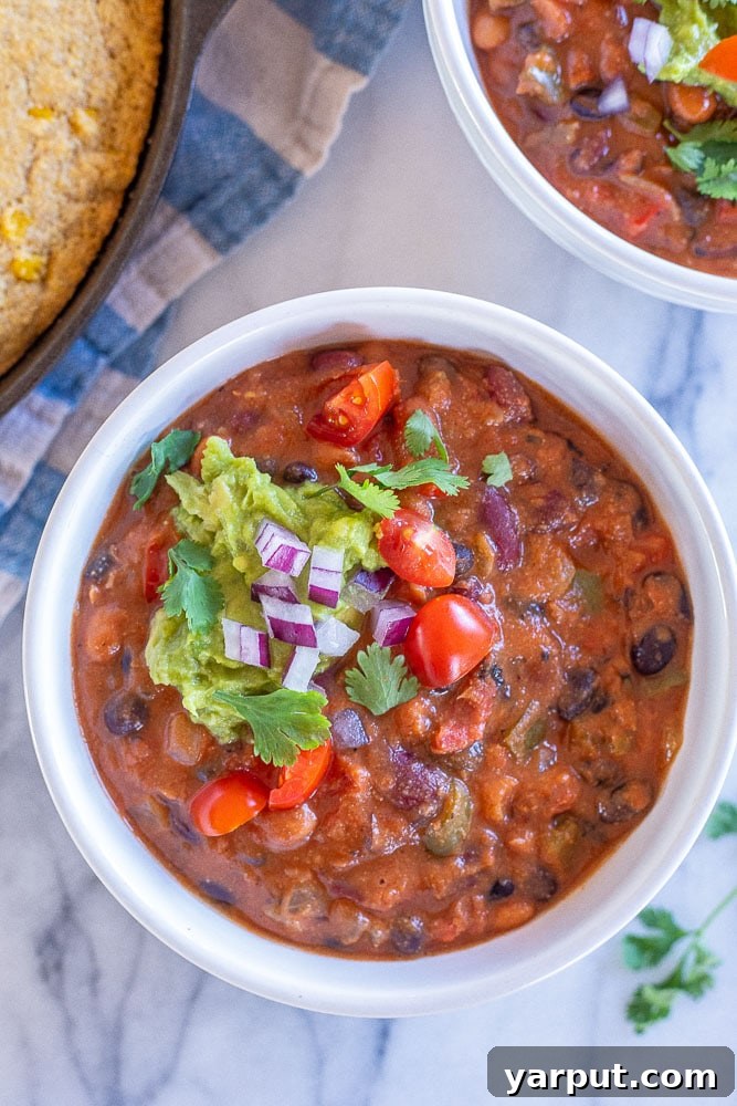 Thick and hearty vegan chili served with tortilla chips and avocado