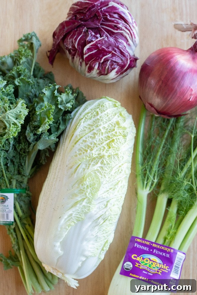 Merry & Bright Coleslaw 3 Variety of fresh vegetables including cabbage, kale, radicchio, fennel, and red onion, laid out on a wooden board ready for chopping.