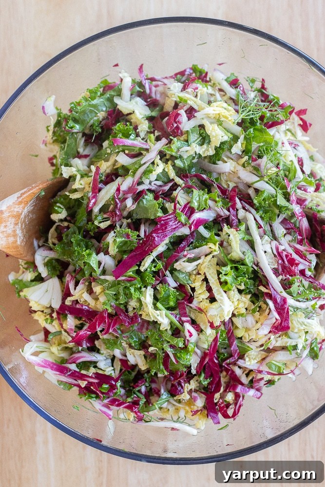 Merry & Bright Coleslaw 6 Finely shredded coleslaw greens, including kale, radicchio, and cabbage, all mixed together in a large bowl, ready for dressing.