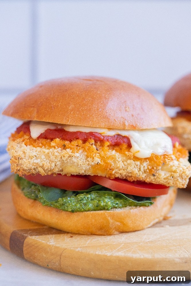 Week 17: Simple Plant-Based Meal Ideas 7 A close-up of a delicious vegetarian 'chicken' parmesan sandwich, featuring crispy tofu, marinara sauce, and melted cheese, ready to be enjoyed.