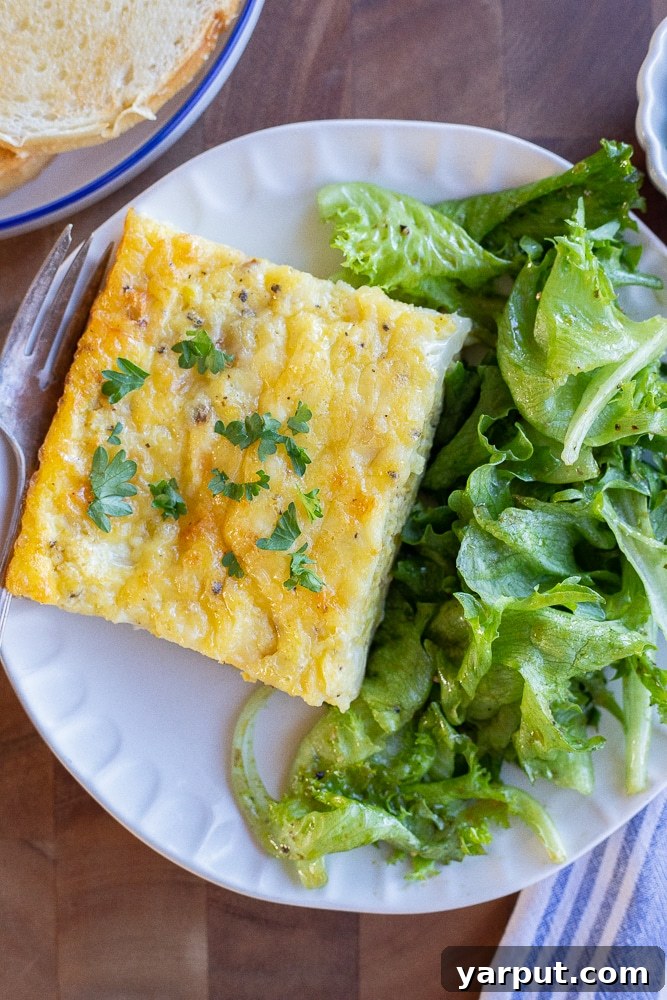 Baked Eggs with White Cheddar, Leeks, and Cauliflower 7 A breakfast table set with a beautifully baked Cauliflower Leek and White Cheddar Egg Bake, sliced and ready to serve, accompanied by a fresh green salad and toasted bread.
