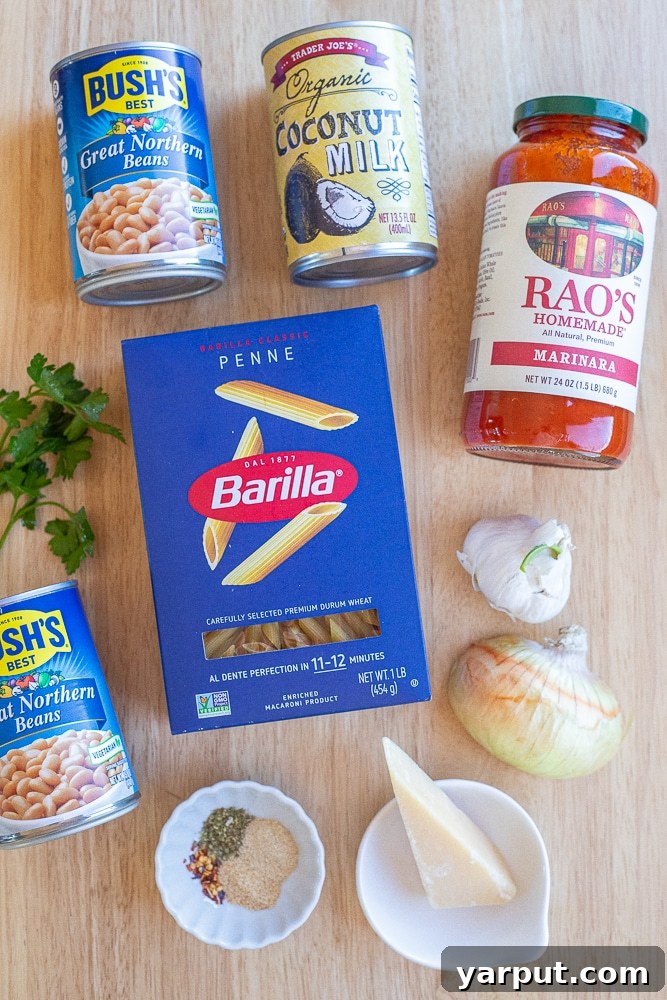 All the fresh and pantry ingredients needed to make this creamy tomato pasta with white beans recipe, neatly arranged