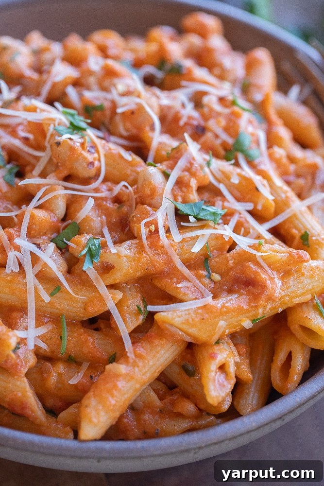 close up of a bowl of creamy red pasta with white beans, ready for a comforting meal