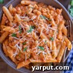close up of creamy tomato pasta with white beans in a bowl