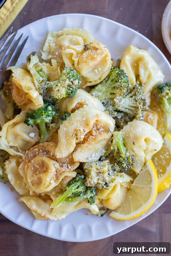 Zesty Roasted Lemon Parmesan Tortellini with Broccoli 2 Close-up of a perfectly plated serving of roasted tortellini with broccoli, generously topped with grated Parmesan cheese, showcasing its golden-brown texture and vibrant green broccoli florets.