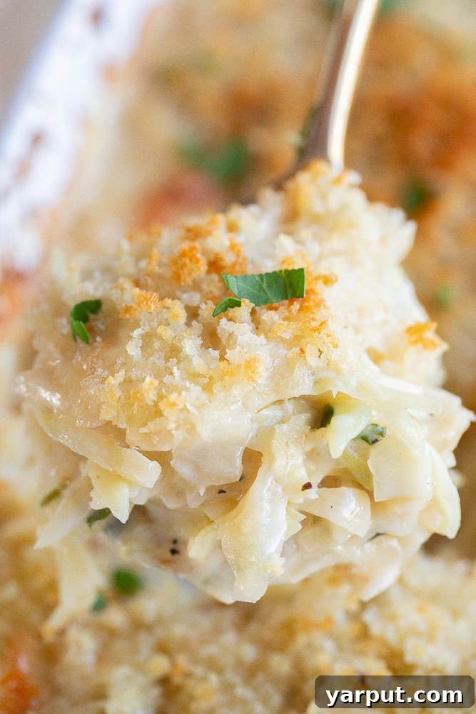 Golden Cheesy Cabbage Bake 6 A serving spoon lifting a portion of cheesy baked cabbage from a casserole dish, ready to be served.