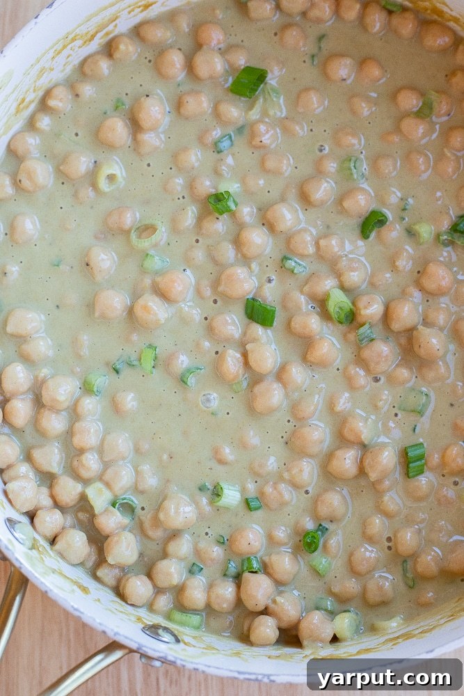 Fragrant Green Curry Chickpeas in Minutes 5 A pan full of simmering chickpeas coated in a rich and flavorful green curry sauce.