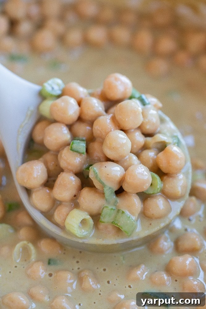 Fragrant Green Curry Chickpeas in Minutes 6 A soup ladle brimming with creamy, curried chickpeas, ready to be served into a bowl.