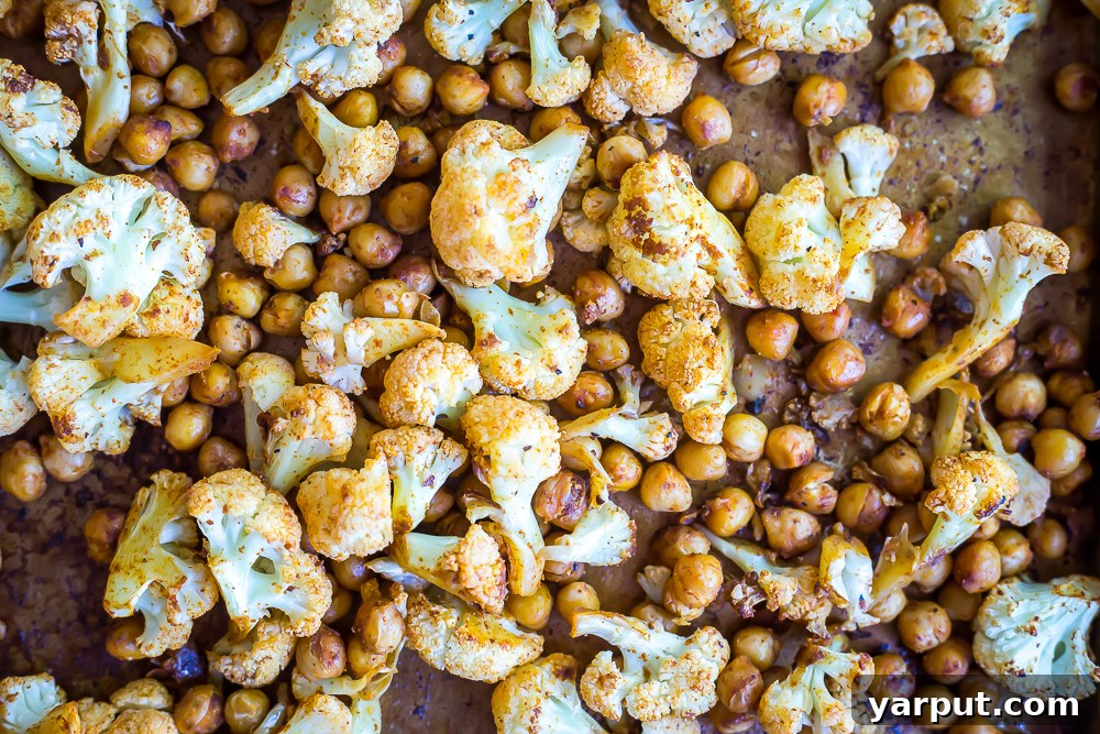 Expertly coated cauliflower and chickpeas with a rich BBQ rub, ready for roasting to achieve perfect flavor and texture.