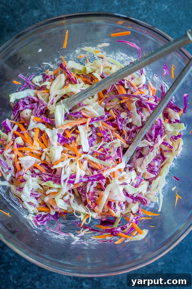 Freshly prepared creamy lime slaw, featuring shredded cabbage and carrots dressed in a vibrant, zesty sauce.
