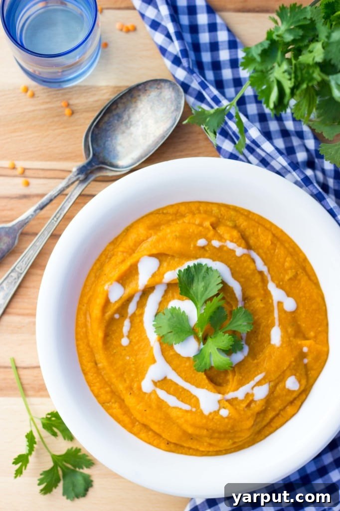 Bowl of Curried Sweet Potato, Carrot, and Red Lentil Soup on a wooden surface