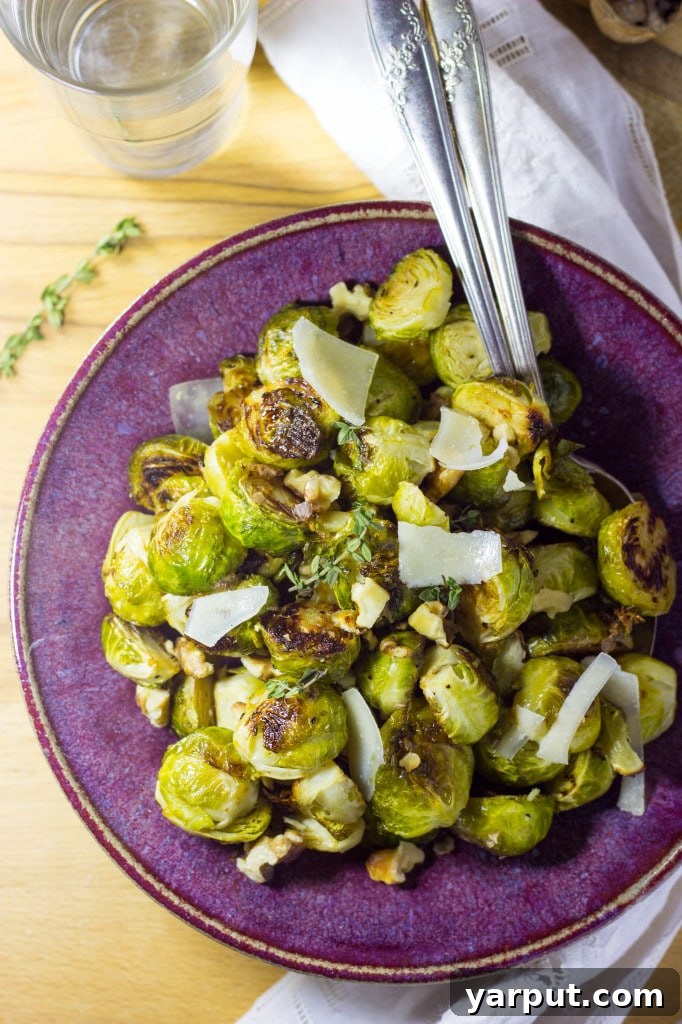 Sweet & Tangy Roasted Brussels Sprouts with Toasted Walnuts and Parmesan 6 Hand reaching for a roasted Brussels sprout