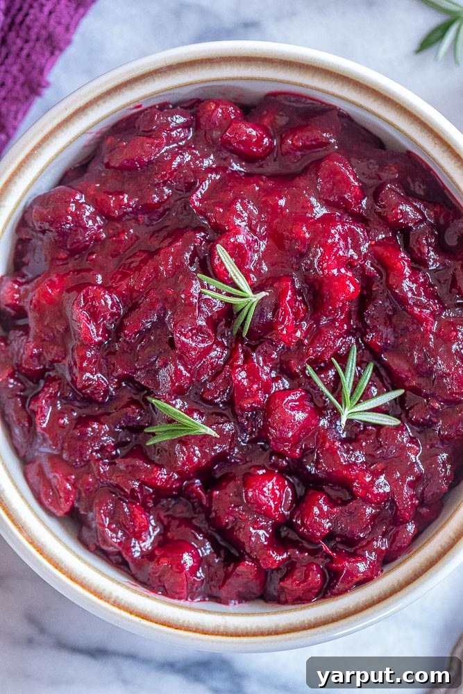 Zesty Orange Ginger Cranberry Sauce 5 Close up of orange ginger cranberry sauce in a bowl with a spoon, ready to be served