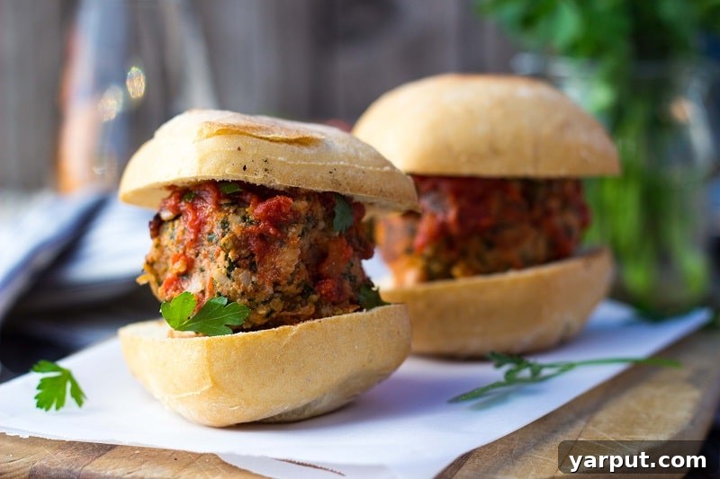 Plant-Powered Feta and Kale Sliders with White Beans 7 Two vegetarian meatball sliders on a wooden cutting board, ready to be eaten