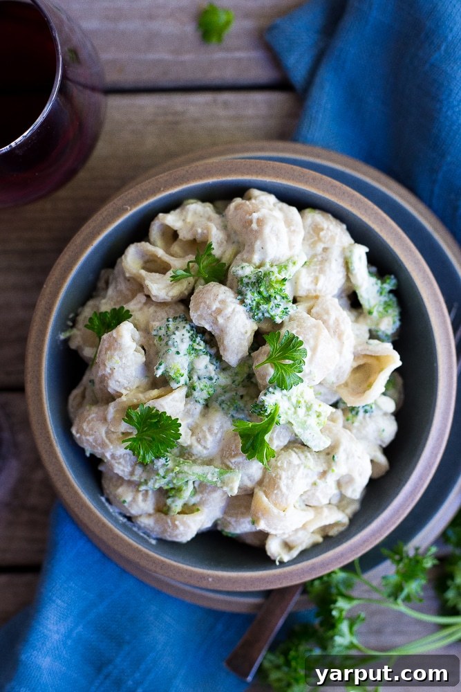 Creamy Plant-Based Cashew Alfredo Pasta with Broccoli 5 A serving of creamy vegan alfredo pasta with fresh broccoli, garnished with parsley and black pepper, ready to be enjoyed as a healthy and satisfying meal.