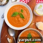 A bowl of chilled cherry tomato soup garnished with fresh basil
