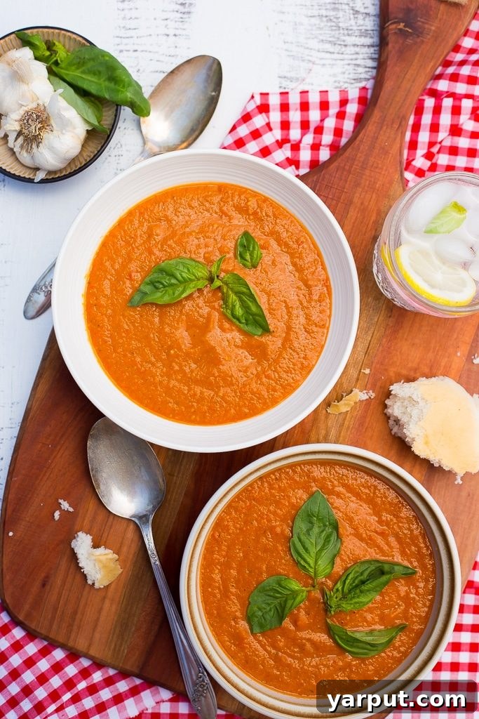 A close-up of chilled cherry tomato soup with basil garnish in a rustic bowl
