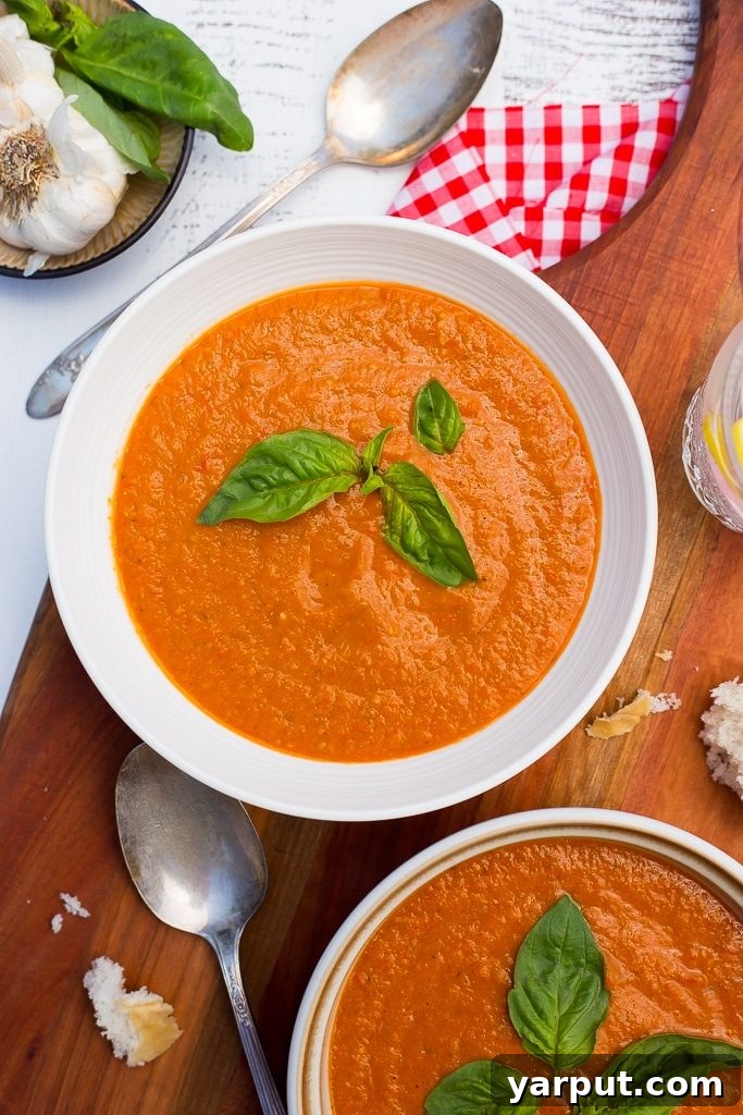 Overhead shot of two bowls of chilled cherry tomato soup on a wooden table