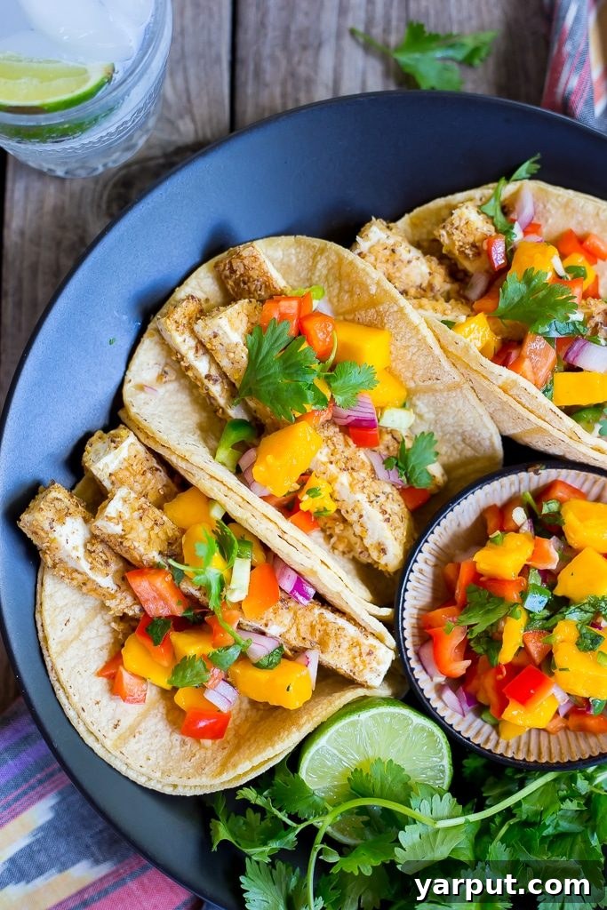 Golden Crunch Tofu Tacos with Sunny Mango Salsa 8 A perfectly assembled tortilla chip crusted tofu taco with vibrant mango salsa, garnished with fresh cilantro.