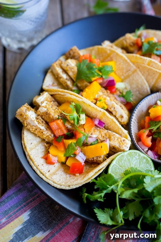Golden Crunch Tofu Tacos with Sunny Mango Salsa 9 Hand holding a delicious crispy tofu taco with mango salsa, showcasing the vibrant colors and appealing texture.