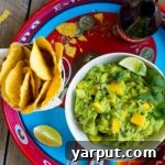 A close-up of delicious Mango Black Bean Guacamole with tortilla chips, ready to be enjoyed.