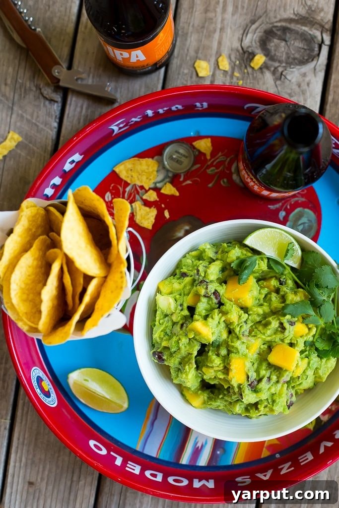 A large bowl of Mango Black Bean Guacamole, garnished with fresh cilantro, ready to be served. Ideal for parties or a healthy snack.