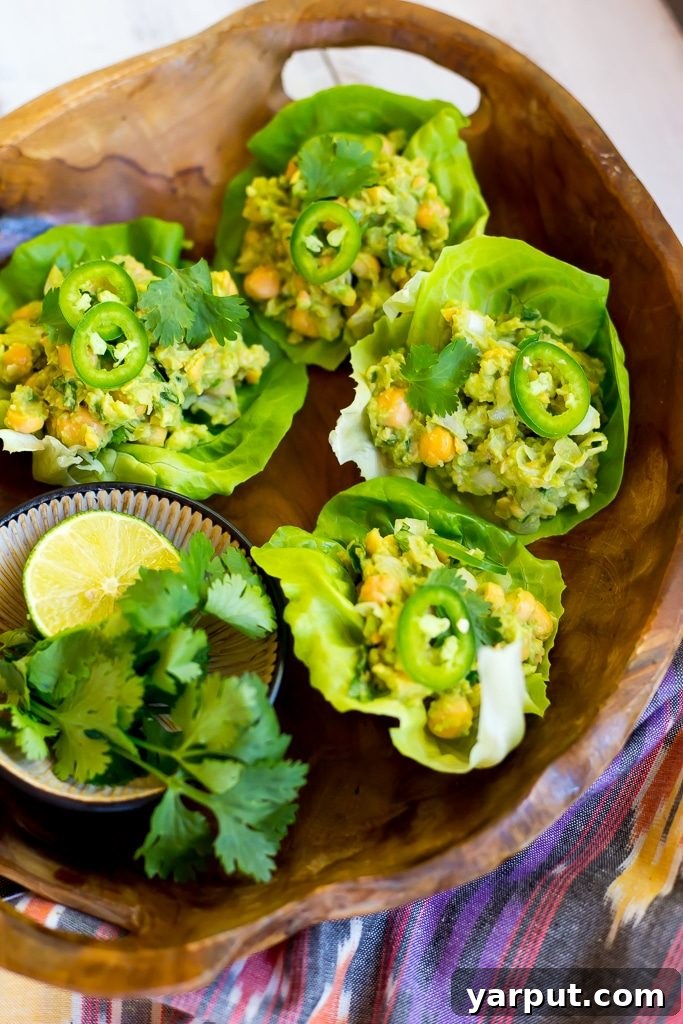 Creamy Chickpea Avocado Lettuce Bites 7 A stack of Chickpea Avocado Lettuce Wraps garnished with fresh herbs, appealing and healthy.