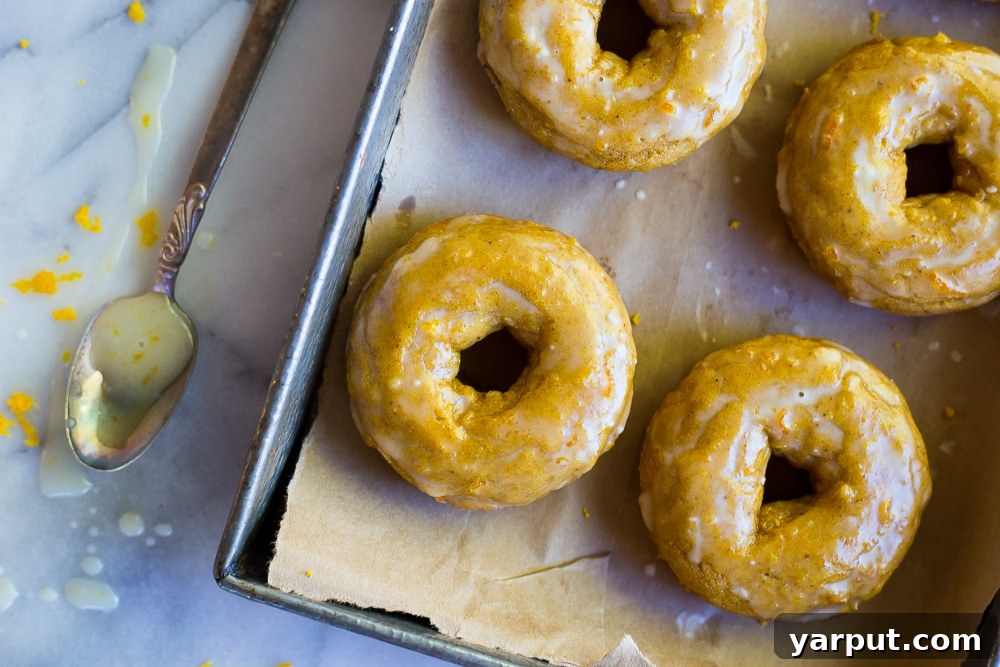 Pumpkin Doughnuts with Orange Glaze (Gluten-Free) 4 Close-up view of perfectly baked Gluten-Free Pumpkin Doughnuts with a luscious orange glaze drizzled over them, highlighting their appealing texture and inviting autumn colors.