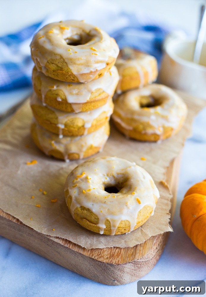 Pumpkin Doughnuts with Orange Glaze (Gluten-Free) 5 A close-up of a single perfectly baked Gluten-Free Pumpkin Doughnut, rich with autumn spices and generously coated in a bright orange glaze, resting on a wire rack, ready to be enjoyed.
