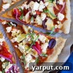 Top down view of a baked Vegan Greek Pizza with golden crust and fresh basil