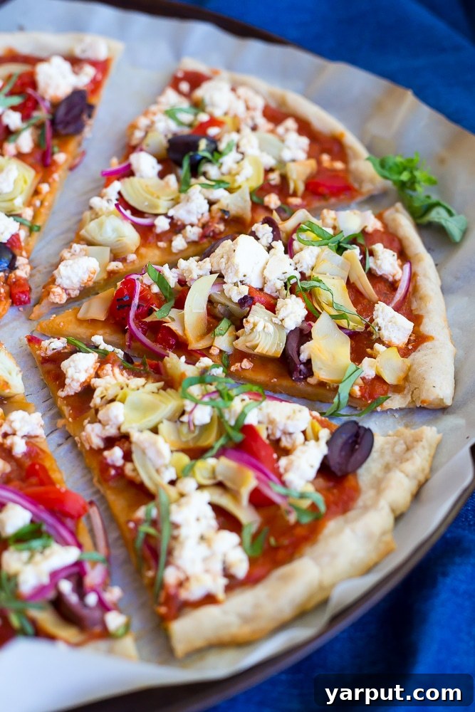 Plant-Based Greek Pizza Gluten-Free 5 Two hands holding a slice of Vegan Greek Pizza, showcasing the gluten-free crust and colorful toppings