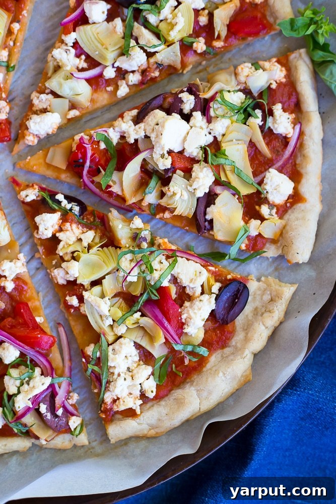 Plant-Based Greek Pizza Gluten-Free 6 A whole Vegan Greek Pizza on a wooden board, ready to be served, with fresh basil garnish