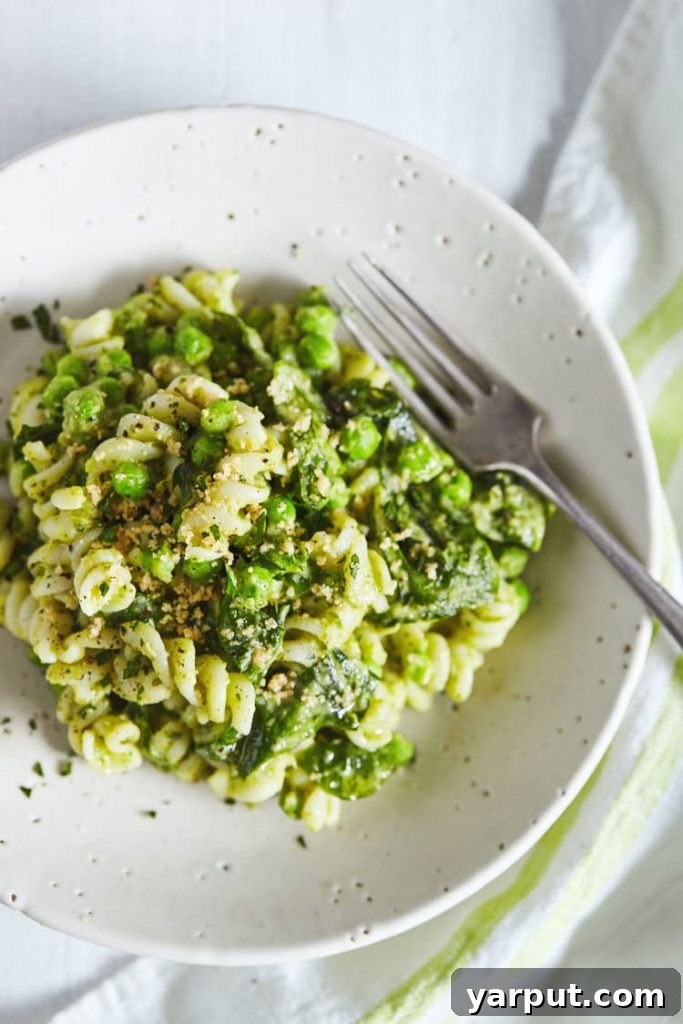 Meatless Muscle 35 Protein Rich Pasta Creations 5 A large serving of Creamy White Bean Pesto Pasta, garnished with fresh basil, ready to be enjoyed as a hearty vegetarian dish.