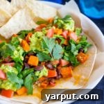 A vibrant, healthy vegetarian 7-layer burrito filled with quinoa, roasted sweet potatoes, and black beans on a plate.