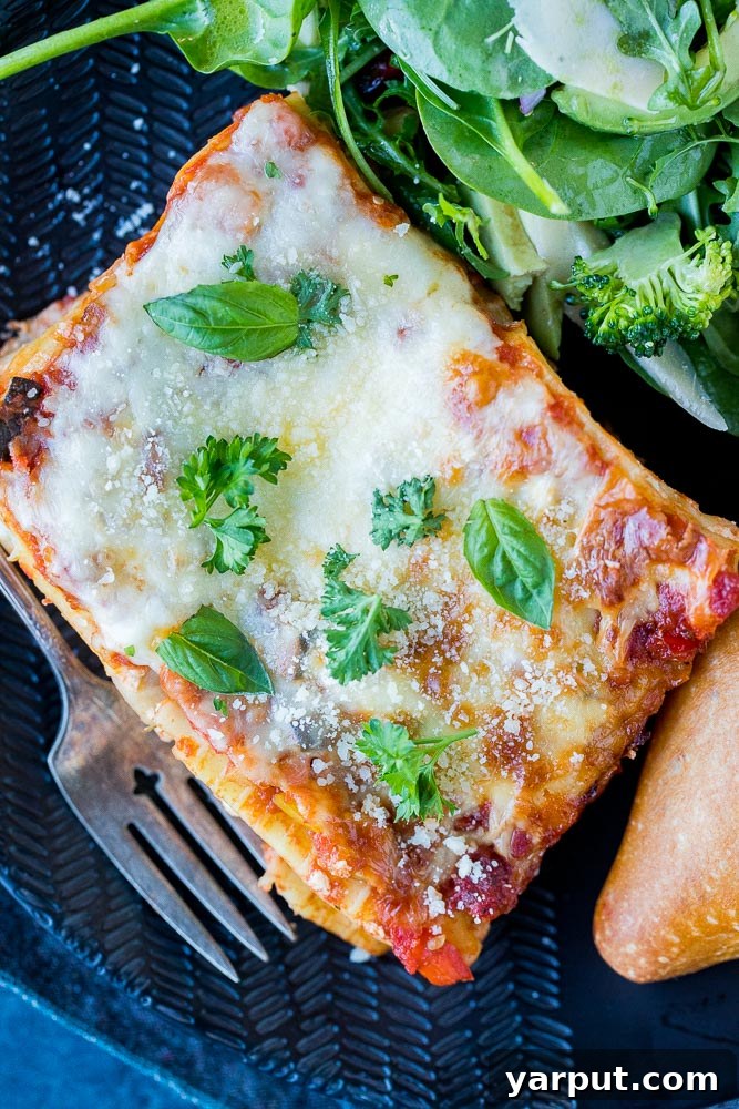 Perfect Plant-Based Lasagna 7 A large, inviting slice of vegetarian lasagna, bursting with layers of pasta, vegetables, and melted cheese, served on a white plate with a side of fresh salad, ready to be enjoyed.