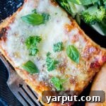 The Best Vegetable Lasagna, showcasing a generous slice with golden melted cheese and visible layers of pasta and vegetables.