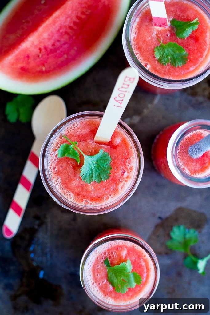 Sadece Karpuzla Buz Gibi Serinlik! 5 Two glasses of watermelon slushie, garnished with mint and lime, served on a textured wooden table.