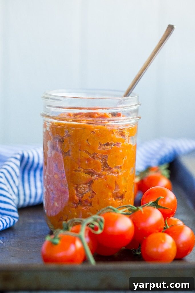 Effortless Cherry Tomato Preserve 4 Cherry Tomato Jam in a glass jar with fresh basil, showcasing its rich, thick texture. This homemade jam is an excellent summer condiment.