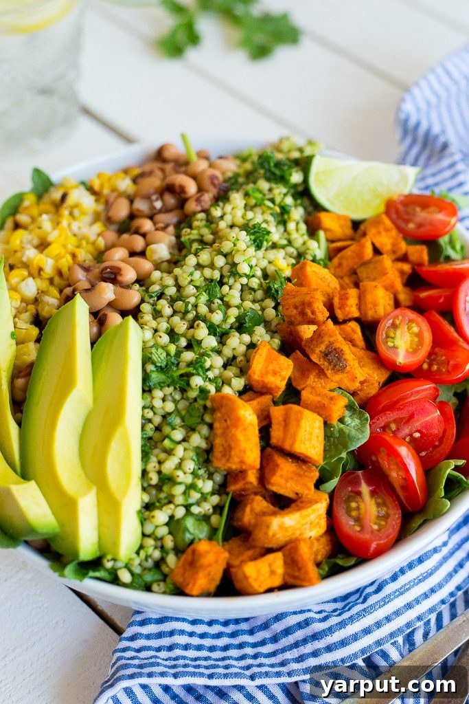 Side view of a Green Sorghum Burrito Bowl, showcasing layers of sorghum, sweet potato, and fresh toppings.