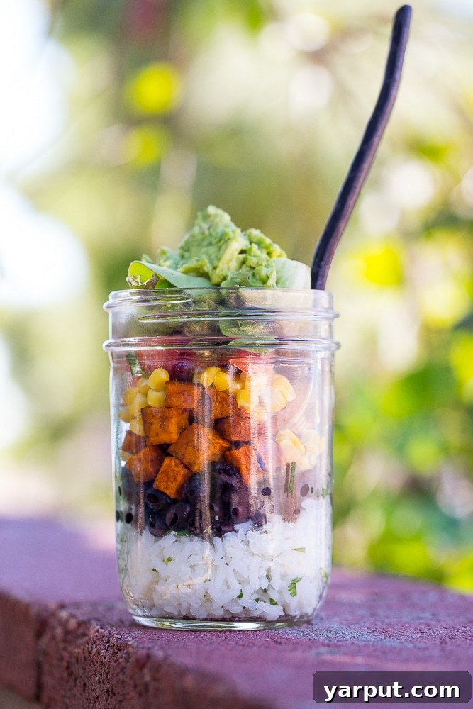 Portable Plant-Based Burrito Bowls 3 Overhead view of two neatly layered Vegetarian Mason Jar Burrito Bowls, ready for refrigeration. Each jar features distinct colorful layers of ingredients, promising a fresh and balanced meal.