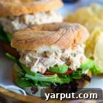 Beautifully plated chickpea and white bean salad sandwiches on a cutting board with fresh ingredients.