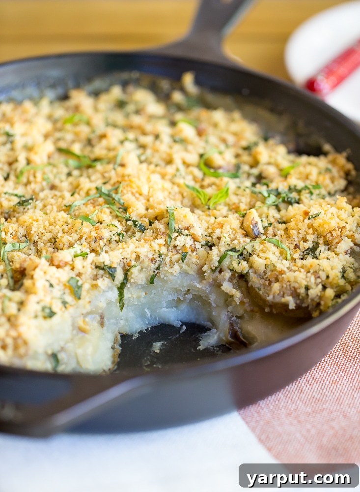 Layered Vegan Scalloped Potatoes in a baking dish, showcasing the creamy sauce and thinly sliced potatoes before baking.
