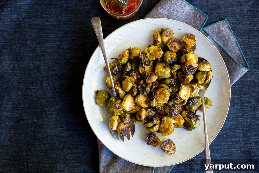 Sweet Heat Roasted Brussels Sprouts 3 Close-up of freshly roasted Brussels sprouts being tossed with sweet chili sauce, highlighting the glaze and inviting texture. Vegan and gluten-free.