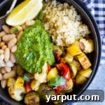 A beautifully presented Roasted Veggie Buddha Bowl with fresh pesto, ideal for a healthy and satisfying meal.